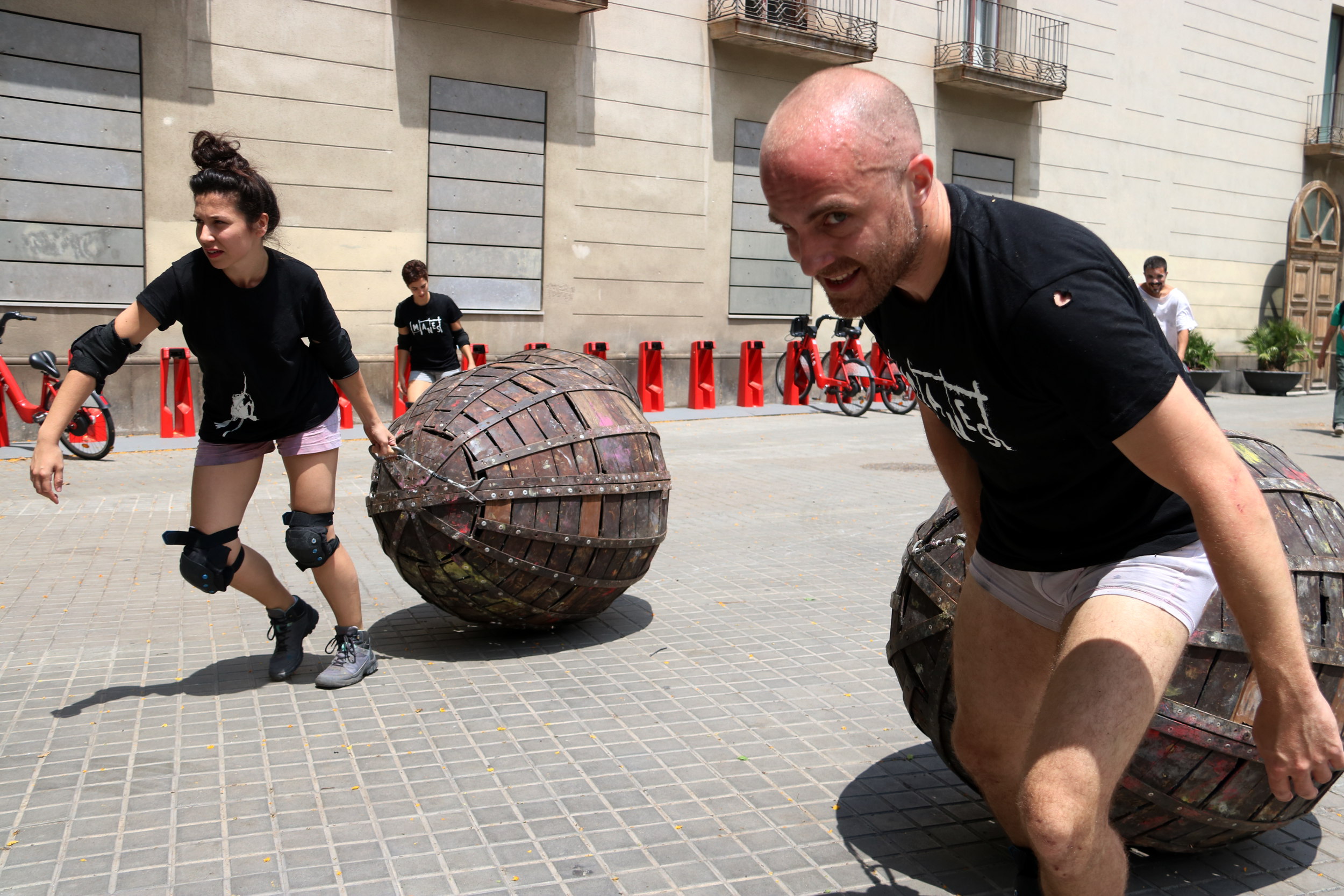 La Fura dels Baus actors drag metal eggs containing other actors near Barcelona's Maritime Museum on July 9, 2019 (Pau Cortina/ACN)